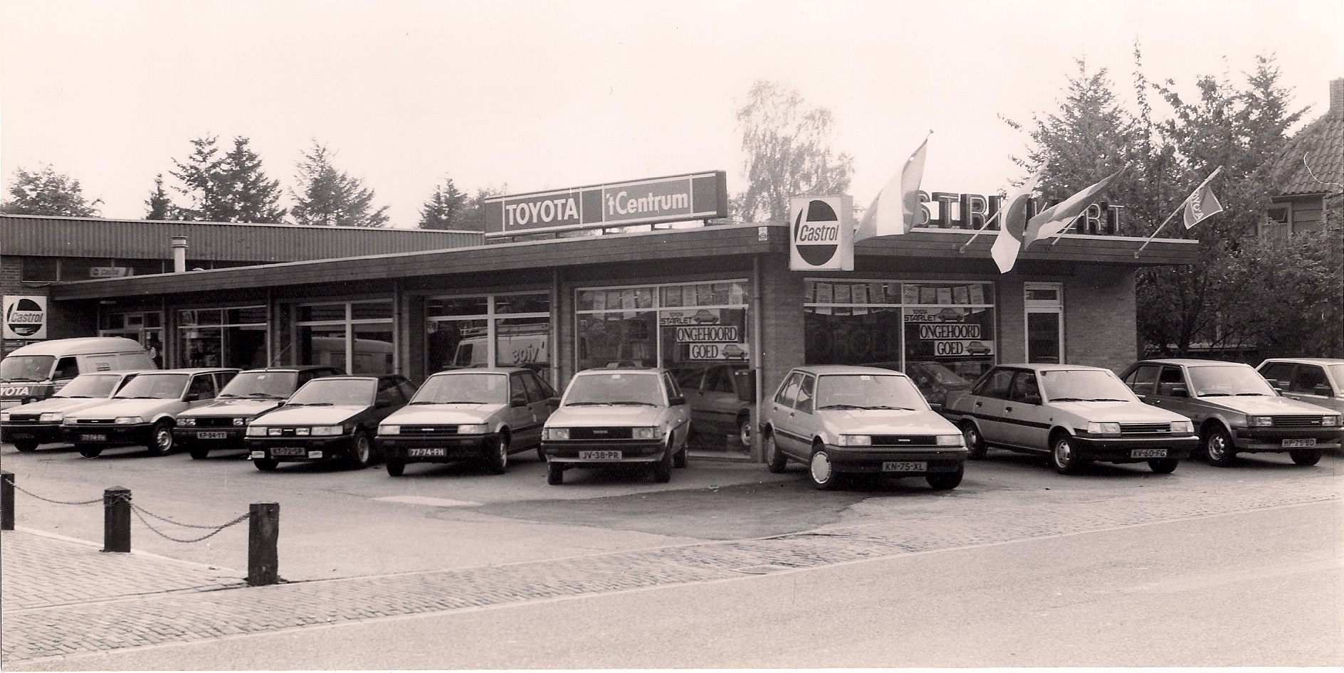 Zwart-witfoto van de showroom in de Toyota-jaren, met een rij Toyota Starlets en de naam Strijkert op de gevel